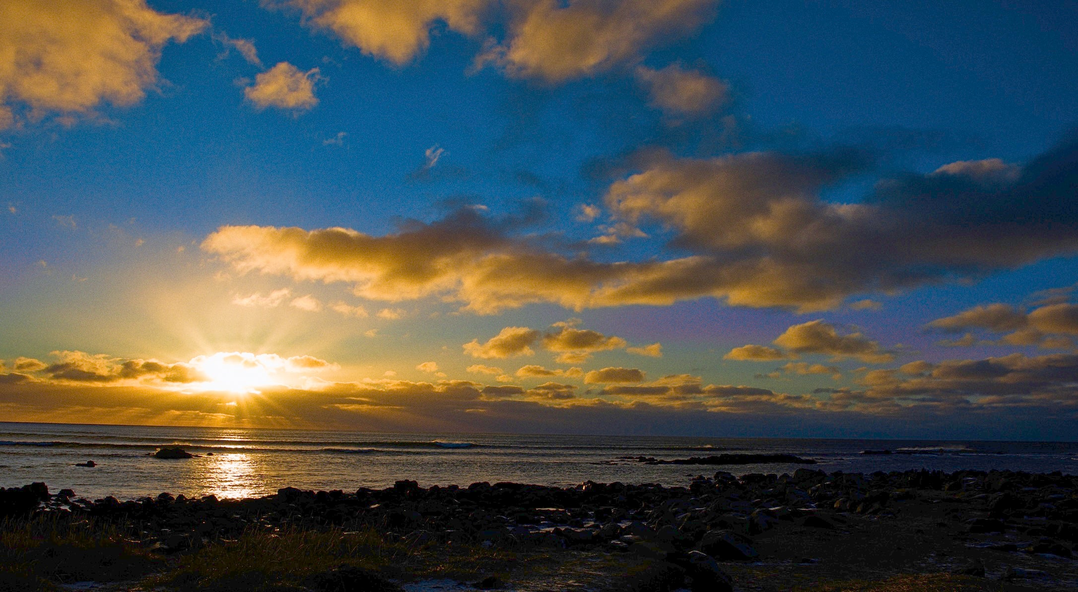 Icelandic Winter Sunrise over a beach with dark clouds and reflective water.